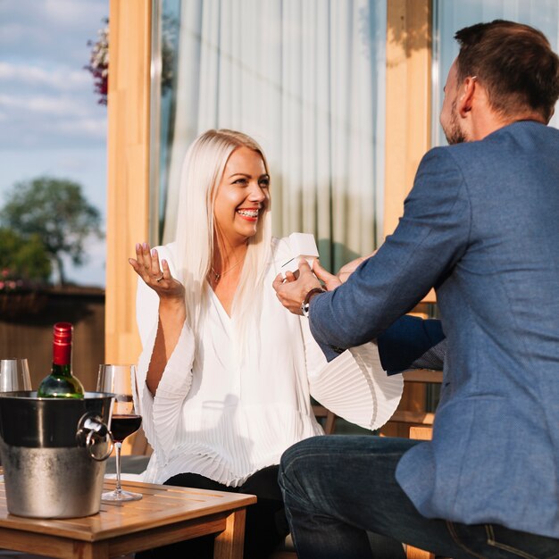 Hombre mostrando un anillo de compromiso a su novia feliz en un restaurante