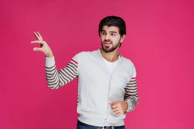 Hombre mostrando las dimensiones o medidas de un objeto.