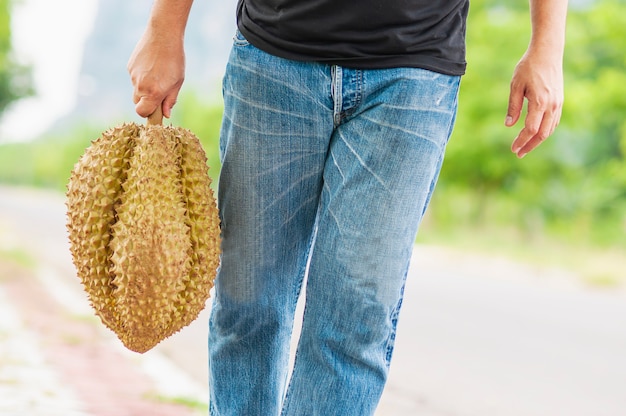Hombre mostrando durian maduro felizmente