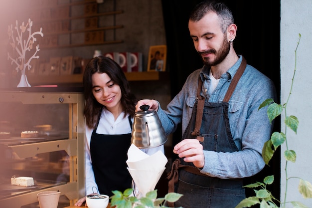 Hombre mostrando empleado cómo verter café en filtro