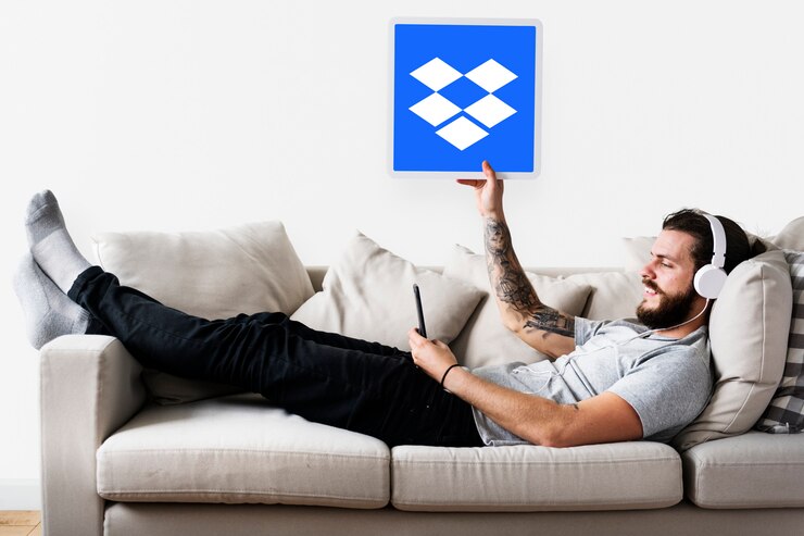 Foto gratuito hombre mostrando un icono de dropbox en un sofá