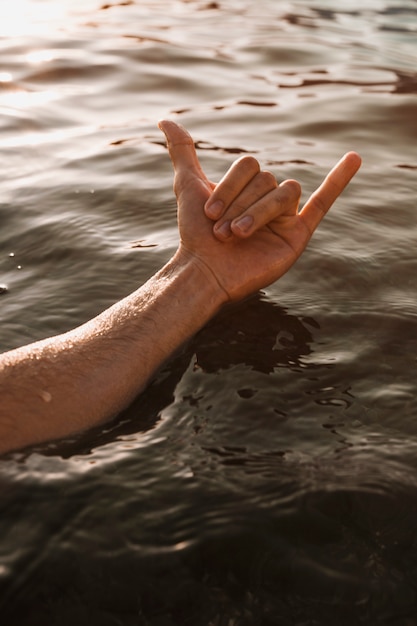 Foto gratuita hombre mostrando signo de mano shaka en agua