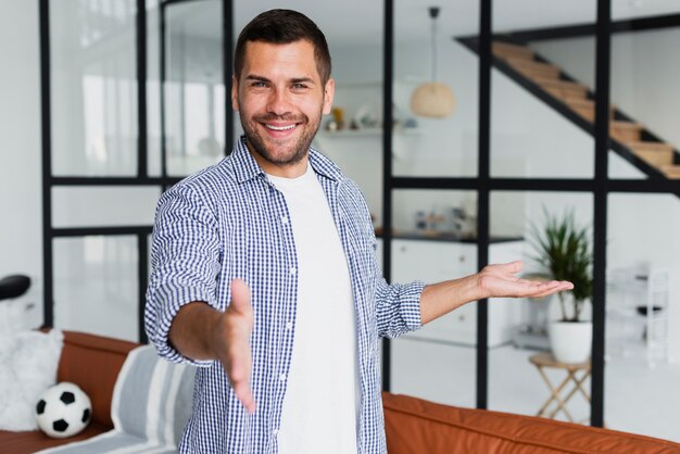 Hombre mostrando sus habitaciones y sonriendo a la cámara