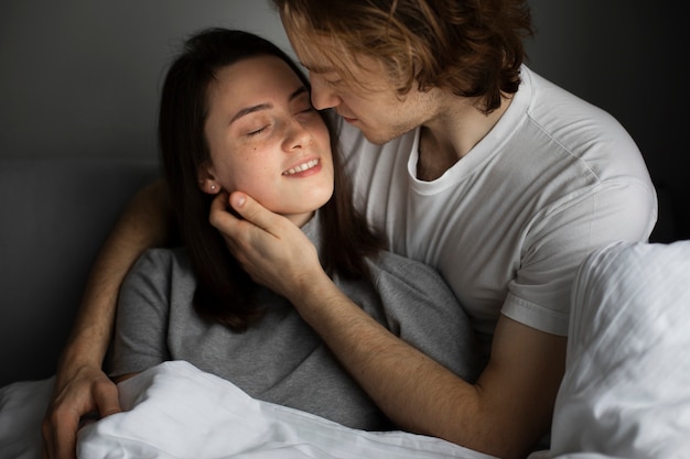 Hombre y mujer abrazados mientras sonríe en la cama