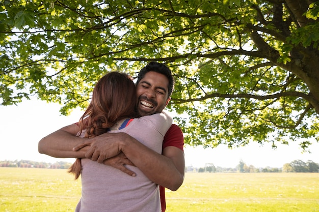 Foto gratuita hombre y mujer abrazándose antes de hacer yoga al aire libre