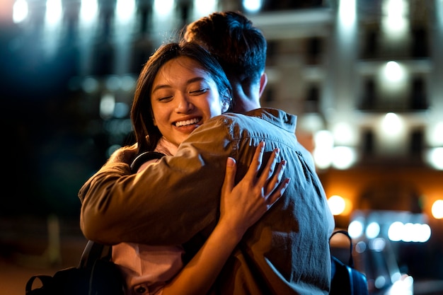 Hombre y mujer abrazándose por la noche en las luces de la ciudad