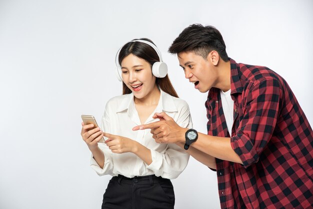 El hombre y la mujer aman escuchar música en sus teléfonos inteligentes