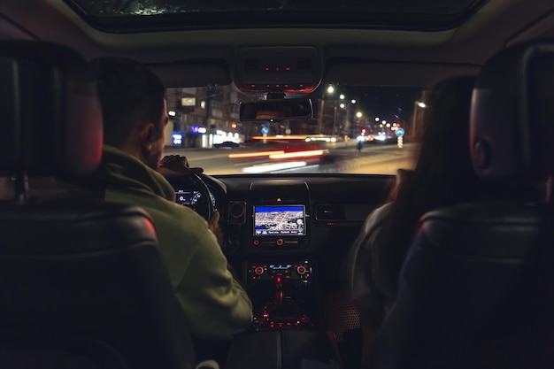 Hombre y mujer en un auto en vista nocturna desde el auto
