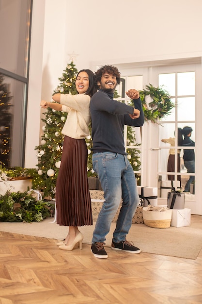 Hombre y mujer bailando espalda con espalda mirando a la cámara