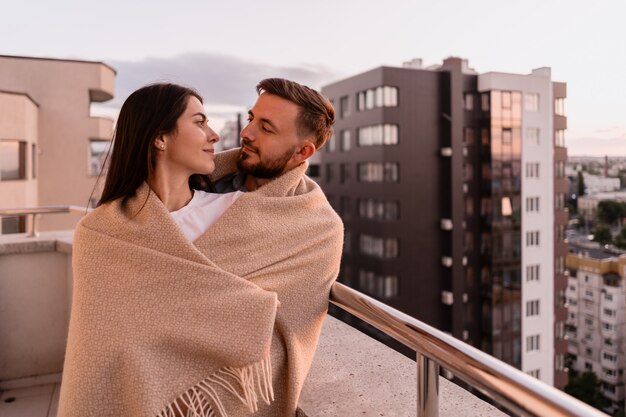 Hombre y mujer en el balcón al atardecer en la ciudad