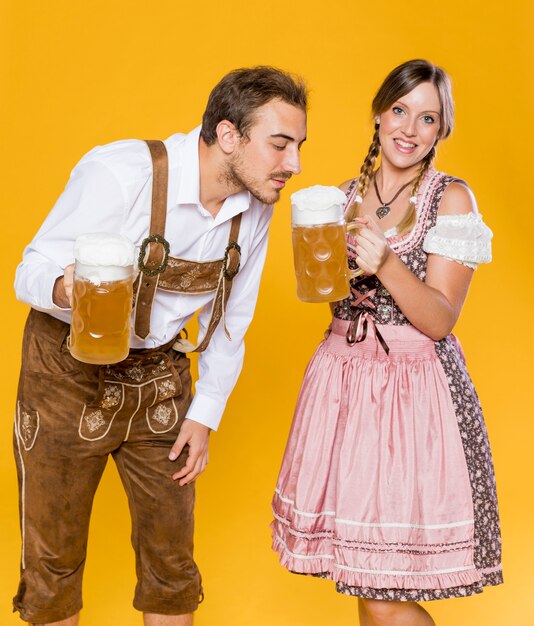 Hombre y mujer bávaros con jarras de cerveza