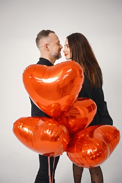 Hombre y mujer besándose cubriendo con un montón de globos rojos en forma de corazón