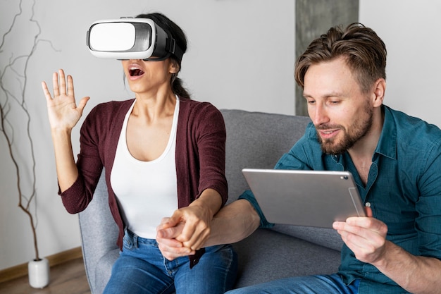 Hombre y mujer en casa con casco de realidad virtual y tableta