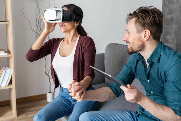 Hombre y mujer en casa con casco de realidad virtual y tableta