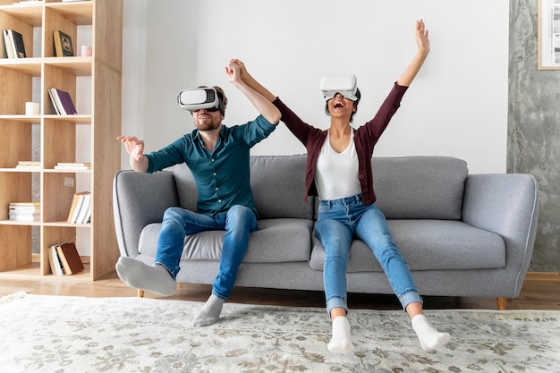 Hombre y mujer en casa en el sofá con casco de realidad virtual