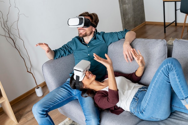 Hombre y mujer en casa en el sofá explorando casco de realidad virtual