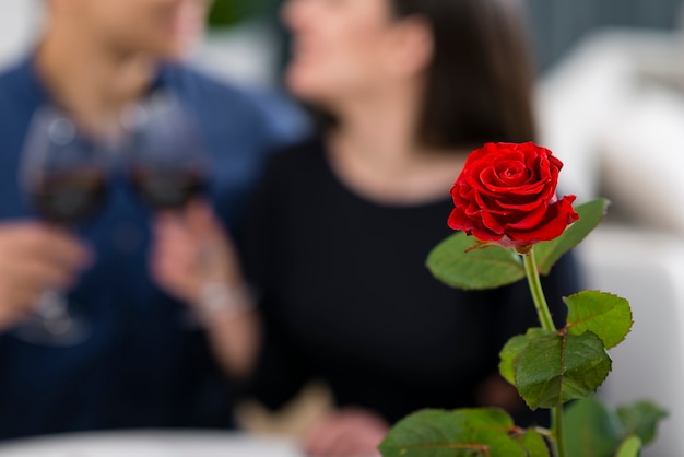 Hombre y mujer con una cena romántica de San Valentín con rosa enfocada