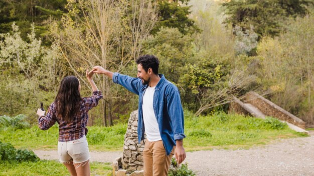 Hombre y mujer con cerveza bailando en la naturaleza