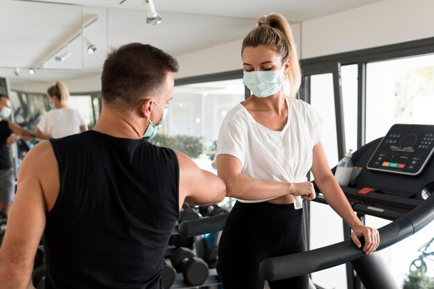 Hombre y mujer con codo para saludarse en el gimnasio