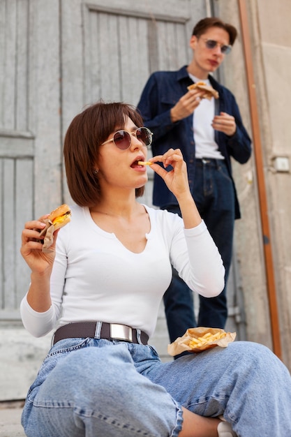 Foto gratuita hombre y mujer comiendo hamburguesas al aire libre