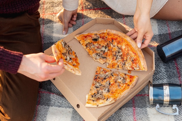 Hombre y mujer comiendo una pizza afuera