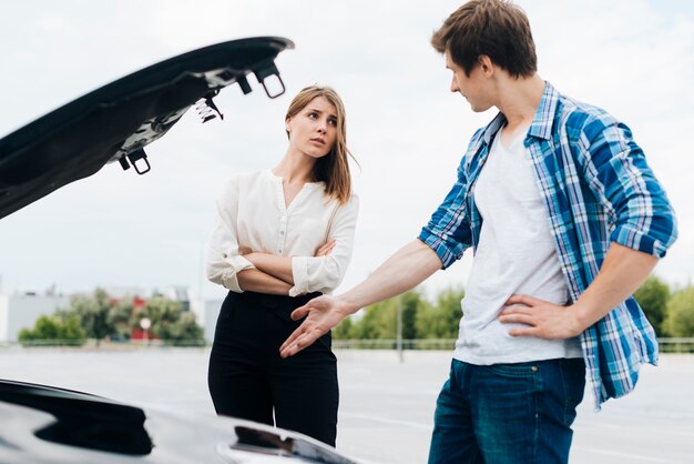 Hombre y mujer comprobando el motor del coche