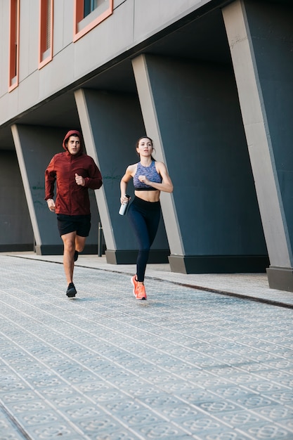 Hombre y mujer corriendo en entorno urbano