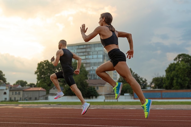 Foto gratuita hombre y mujer corriendo en la vista lateral de la pista