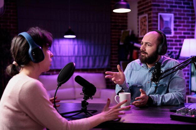 Hombre y mujer creando contenido de podcast en línea con equipo, grabando discusiones en medios sociales. Equipo de personas influyentes que hablan sobre el estilo de vida y el canal de Internet en transmisión en vivo.