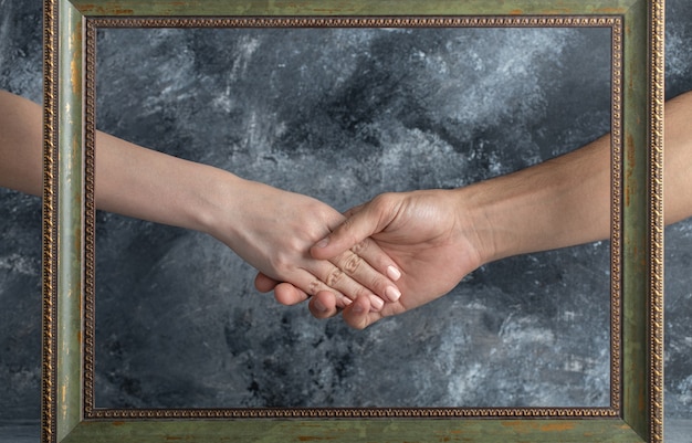 Hombre y mujer dándose la mano en medio del marco de imagen.