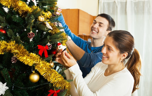 Hombre y mujer decorando el árbol de Navidad