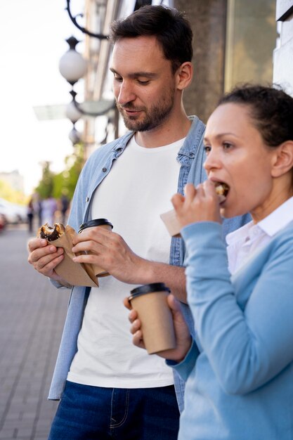 Hombre y mujer disfrutando de comida para llevar en la calle