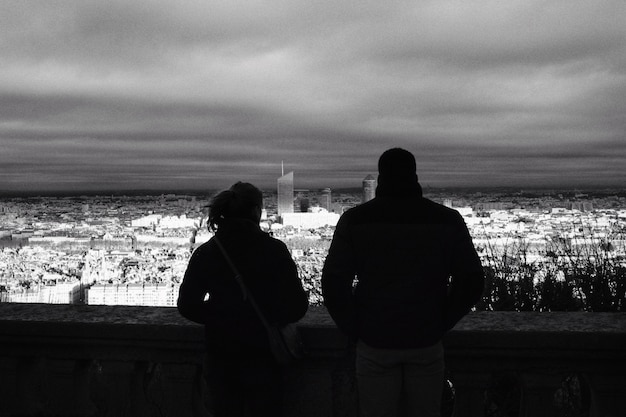 Un hombre y una mujer disfrutando de la vista de la ciudad al atardecer