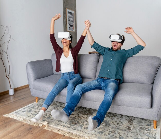 Hombre y mujer divirtiéndose en casa con casco de realidad virtual