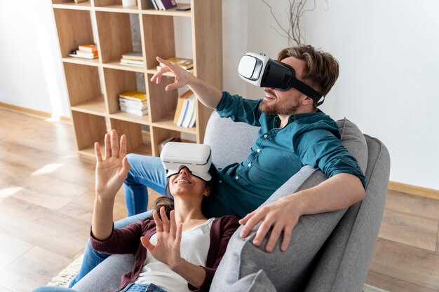 Hombre y mujer divirtiéndose en casa con casco de realidad virtual