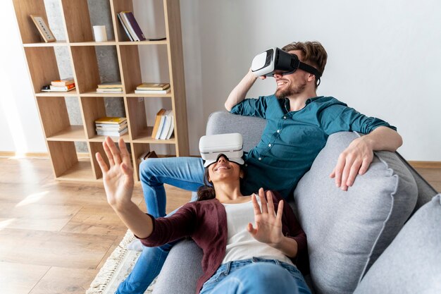 Hombre y mujer divirtiéndose en casa con casco de realidad virtual