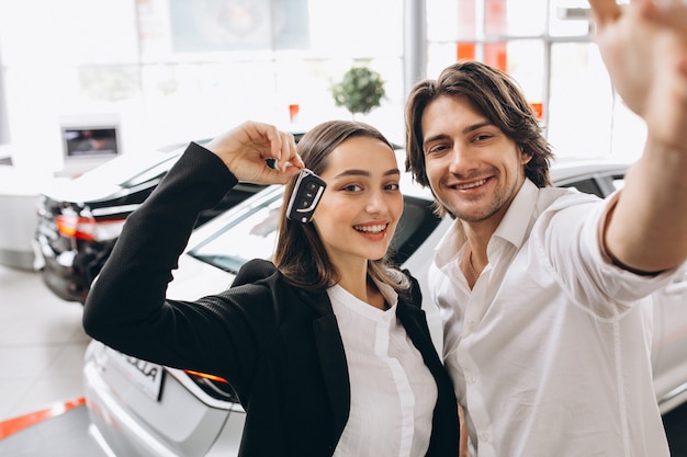 Hombre y mujer eligiendo un automóvil en una sala de exposición de automóviles