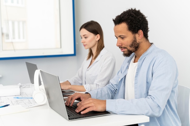 Hombre y mujer escribiendo en un teclado de computadora portátil