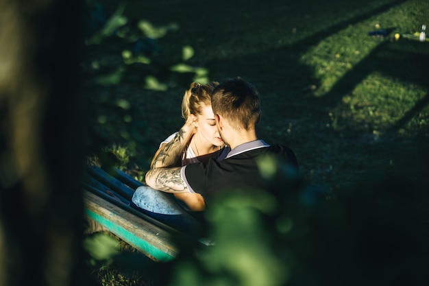 Foto gratuita un hombre y una mujer están sentados en un banco y besándose