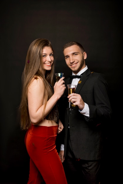 Hombre y mujer felices con copas de bebidas y confeti