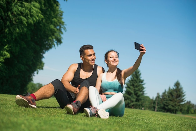 Foto gratuita hombre y mujer haciéndose un selfie en un parque