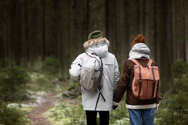 Hombre y mujer joven en un bosque juntos durante un viaje por carretera de invierno