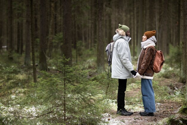 Hombre y mujer joven en un bosque juntos durante un viaje por carretera de invierno