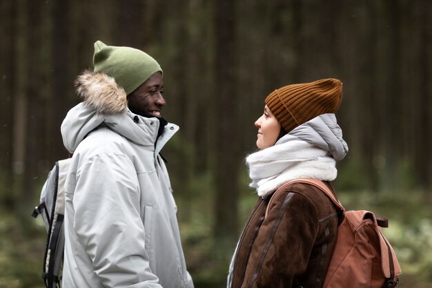 Hombre y mujer joven en un bosque juntos durante un viaje por carretera de invierno