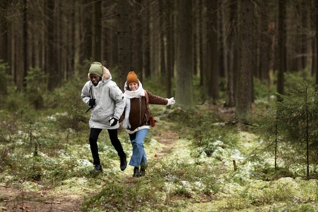 Hombre y mujer joven en un bosque juntos durante un viaje por carretera de invierno