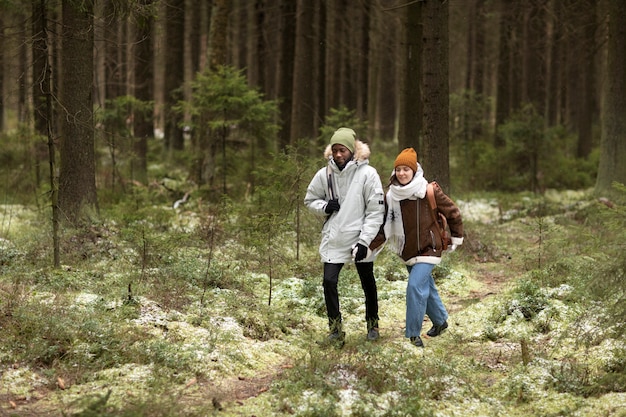 Hombre y mujer joven en un bosque juntos durante un viaje por carretera de invierno