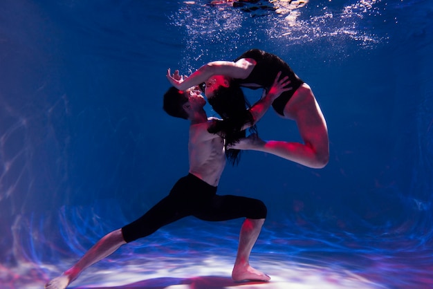 Hombre y mujer joven posando juntos mientras están sumergidos bajo el agua