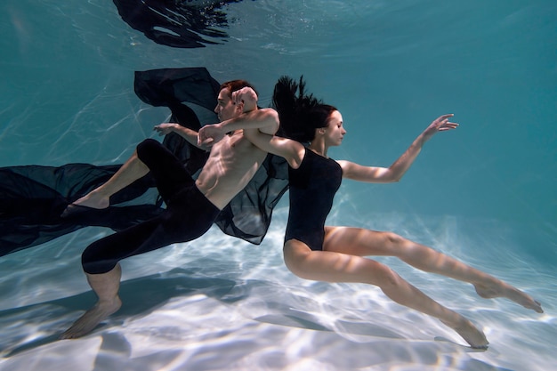 Hombre y mujer joven posando juntos mientras están sumergidos bajo el agua