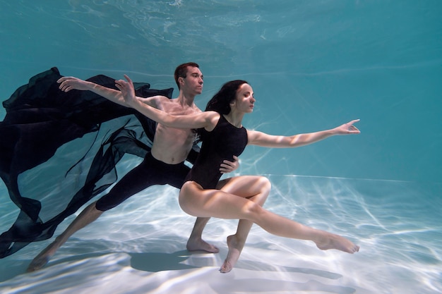 Hombre y mujer joven posando juntos mientras están sumergidos bajo el agua