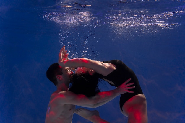 Hombre y mujer joven posando juntos mientras están sumergidos bajo el agua